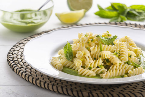 piatto di fusilli con piselli, zucchine e lime