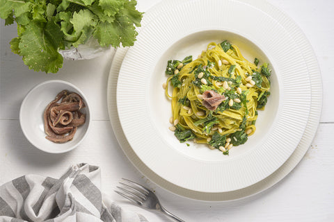 piatto di tagliatelle paglia e fieno con cime di rapa e acciughe