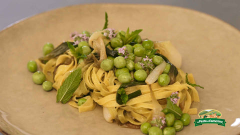piatto di tagliatelle paglia e fieno con cipollotti caramellati, piselli freschi e menta